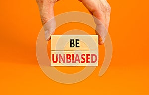 Be unbiased symbol. Concept words Be unbiased on wooden block. Beautiful orange table orange background. Businessman hand.