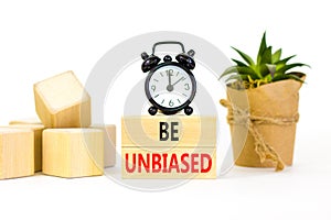 Be unbiased symbol. Concept words Be unbiased on wooden block. Beautiful white table white background. Black alarm clock. Green