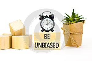 Be unbiased symbol. Concept words Be unbiased on wooden block. Beautiful white table white background. Black alarm clock. Green