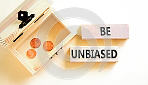 Be unbiased symbol. Concept words Be unbiased on wooden block. Beautiful white table white background. Wooden chest with coins.
