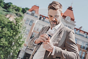 Be undeniably good. Serious brown-haired man standing in the park in the morning. He is going to work.