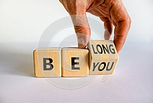 Be you, belong symbol. Businessman hand turns a cube and changes words `be you` to `belong`. Beautiful white background. Busin