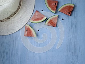 Beach accessories on blue wooden plank  summer holiday on the beach concept  hat and fresh red water melon slicered on wood