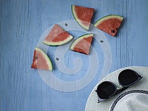 Beach accessories on blue wooden plank  summer holiday on the beach concept  hat and fresh red water melon slicered on wood