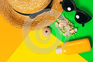 Beach accessories on a bright neon colorful background. A fragment of a straw hat and sea urchin shell , shells necklace, a bottle