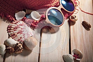 Beach accessories glasses hat cockleshells on wood deck