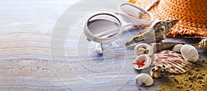 Beach accessories glasses hat cockleshells on wood deck