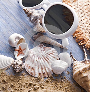 Beach accessories glasses hat cockleshells on wood deck