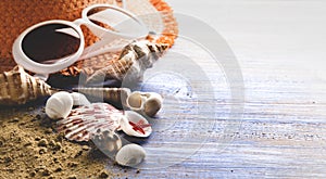 Beach accessories glasses hat cockleshells on wood deck sand