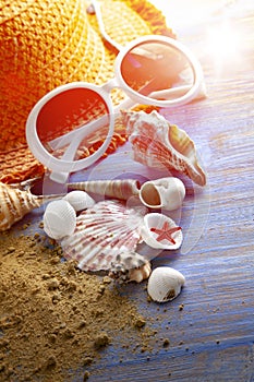 Beach accessories glasses hat cockleshells on wood deck sand