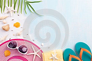 Beach accessories including flip flop, starfish, beach hat and sea shell on sandy beach and blue wooden background for summer