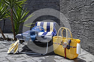 Beach accessories, pool accessories in the garden at home on a sun lounger, flip flops, bag, hat, bikini