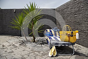 Beach accessories, pool accessories in the garden at home on a sun lounger, flip flops, bag, hat, bikini