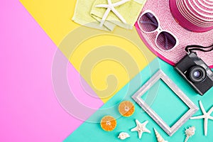 Beach accessories retro film camera, pineapple, sunglasses, flip flop starfish beach hat and sea shell on pink and yellow