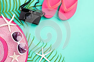 Beach accessories retro film camera, sunglasses, flip flop, starfish beach hat and sea shell on bright pastel green background for