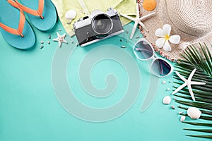 Beach accessories retro film camera, sunglasses, flip flop starfish beach hat and sea shell on green pastel background for summer