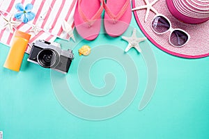 Beach accessories retro film camera, sunglasses, flip flop starfish beach hat and sea shell on green pastel background for summer