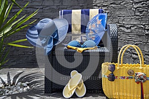 Beach accessories, swimming pool accessories in the garden at home on the couch, bag, hat, bikini, sunglasses, summer weather