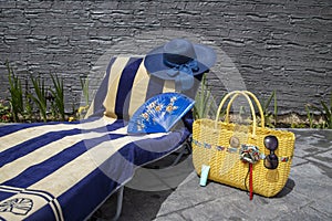 Beach accessories, swimming pool accessories in the home garden on printed concrete, bag, towel, sun lounger