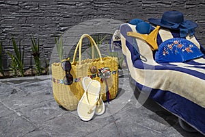 Beach accessories, swimming pool accessories in the home garden on printed concrete, bag, towel, sun lounger