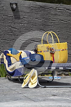 Beach accessories, swimming pool accessories in the home garden on printed concrete, bag, towel, sun lounger