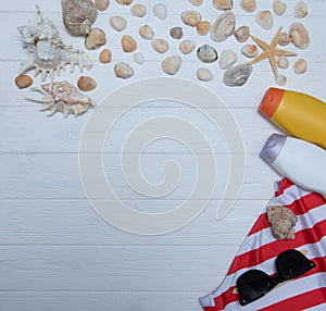 Beach accessories. Towel, flip-flops, starfish, boat and sunglasses on wooden background. Top view with copy space