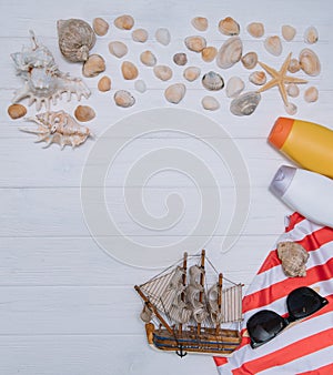 Beach accessories. Towel, flip-flops, starfish, boat and sunglasses on wooden background. Top view with copy space