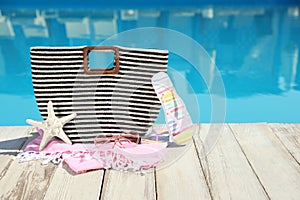 Beach accessories on wooden deck near outdoor  pool, space for text