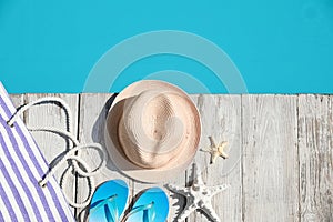 Beach accessories on wooden deck near outdoor swimming pool, flat lay