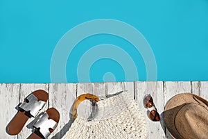 Beach accessories on wooden deck near outdoor swimming pool, flat lay