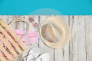Beach accessories on wooden deck near  swimming pool, flat lay
