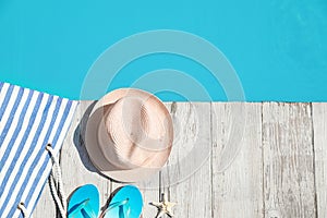 Beach accessories on wooden deck near swimming pool, flat lay. Space for text