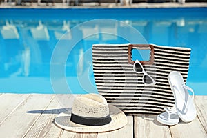 Beach accessories on wooden deck near  swimming pool, space for text