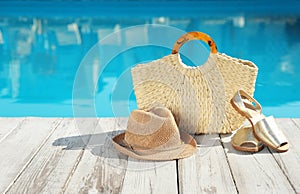 Beach accessories on wooden  near outdoor swimming pool, space for text