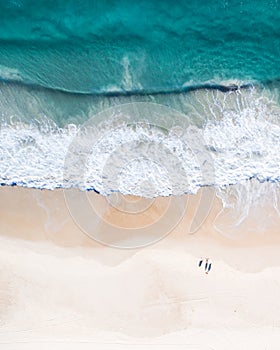 Beach aerial view on the Gold Coast. Nice top view of the blue ocean, crashing wave, white sand and people enjoying a walk.