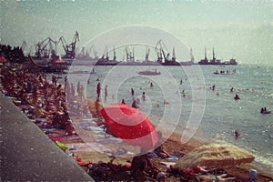 Beach on the background of the seaport and port docks. Retro style, artistic noise. People relax on the beach, next is unloading