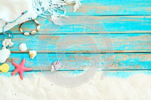 Top viwe of beach sand with white shawl, bracelet made of seashells, starfish, shells and coral on blue wooden background. photo