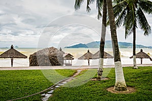 Beach in bad weather. Emptiness, high waves and parasols made of natural materials