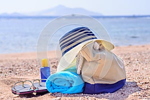 Beach Bag and Sun Hat on Sunny Deserted Beach