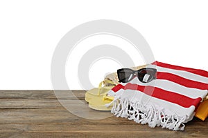 Beach bag with towel, flip flops and sunglasses on wooden surface against white background. Space for text