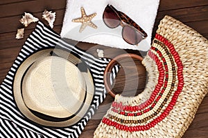 Beach bag with towel, sunglasses on wooden background