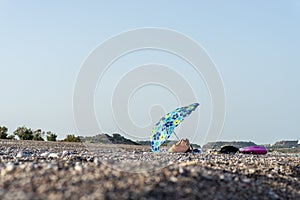 Beach bag and towels under sun umbrella on a beach