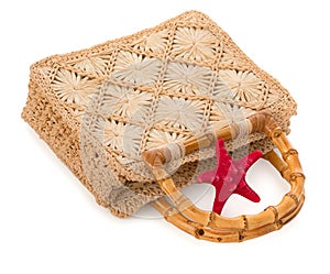 Beach bag of weave reed with bamboo handles and red sea star isolated on white background