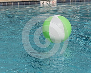 Beach ball in blue swimming pool near depth and no diving sign