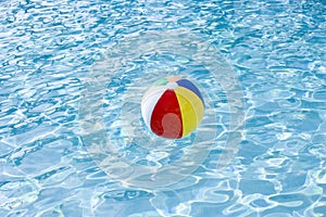 Beach ball floating on surface of swimming pool