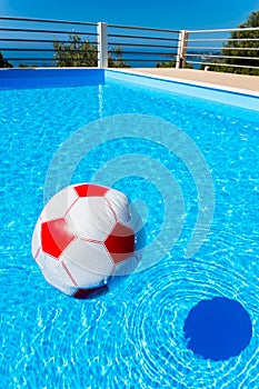 Beach ball floating on water in swimming pool