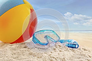 Beach ball and goggles in the sand