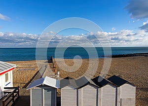 Beach bathing houses beach changing booths / beach huts, rocky beach and sea against blue sky and clouds.