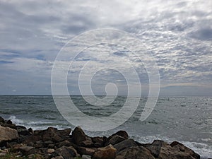 Beach with Black Stones and sky is full of clouds ,sun is also blocked by clouds