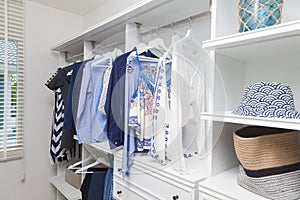 Beach blue clothes hanging in white wardrobe in home